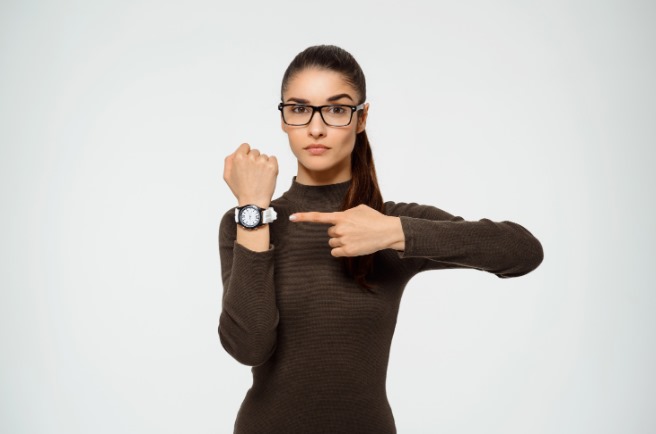 mujer con un reloj en la mano para reducir la impuntualidad en la empresa